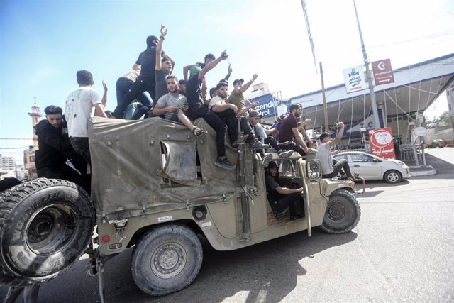 07 October 2023, Palestinian Territories, Gaza City: Palestinian take control of an Israeli military vehicle after crossing the border fence with Israel from Jabalia in the northern Gaza Strip.