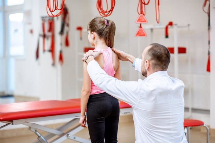 Fisioterapeuta revisando la espalda de una niña.