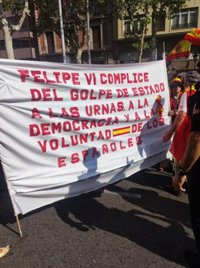 Aparten de la capalera de la marxa de Barcelona dues persones amb una pancarta contra el rei