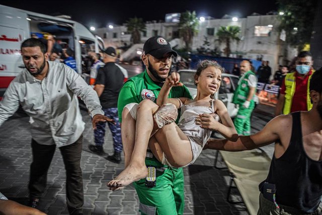 Un paramédico con una niña palestina en brazos en el lugar de un bombardeo