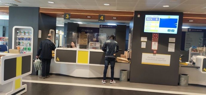 Varias personas en el interior de una oficina de Correos.