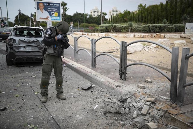 ASHKELON, Oct. 10, 2023  -- An Israeli policeman takes photos of a road damaged by a rocket attack, in Ashkelon, south Israel, Oct. 9, 2023. Israel's state-owned Kan TV reported on Monday that at least 900 were killed by Hamas militants in Israel, while t