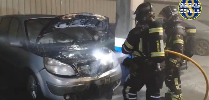 Bomberos sofocando el incendio de un coche en el aparcamiento subterráneo del Virgen del Rocío de Sevilla.