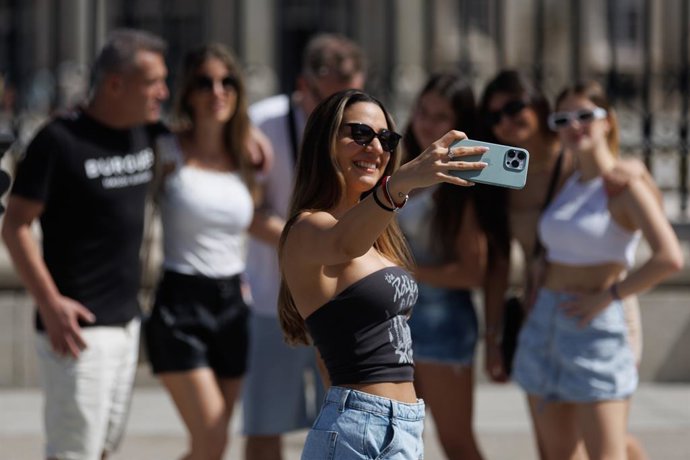 Archivo - Turistas toman fotografías frente al Palacio Real de Madrid, en Madrid (España). 