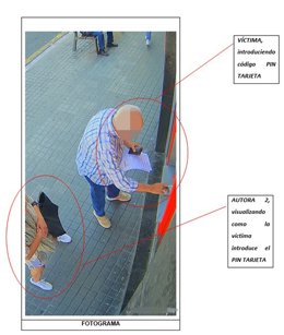 Archivo - Una mujer observa a una persona mayor en un cajero