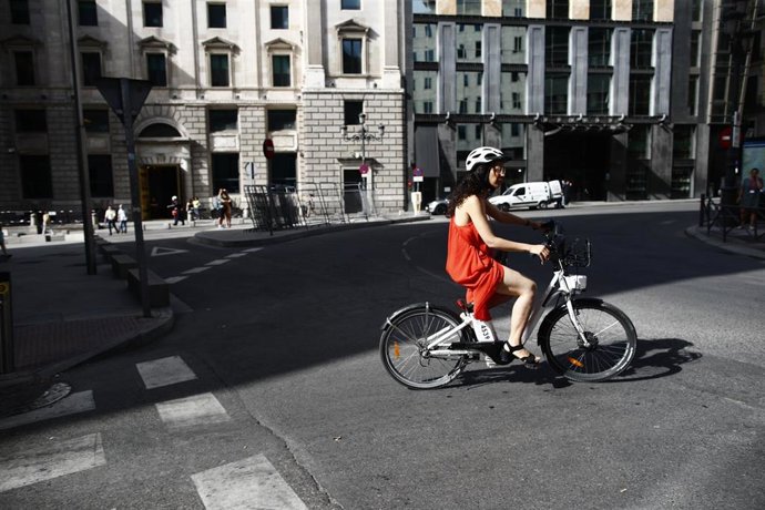 Archivo - Una ciclista pasea con una bicicleta eléctrica cerca del Congreso de los Diputados.