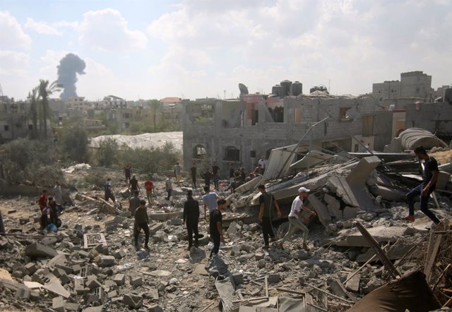 Palestinos buscan entre los escombros de los edificios destruidos tras un ataque israelí en la ciudad de Rafah, Gaza