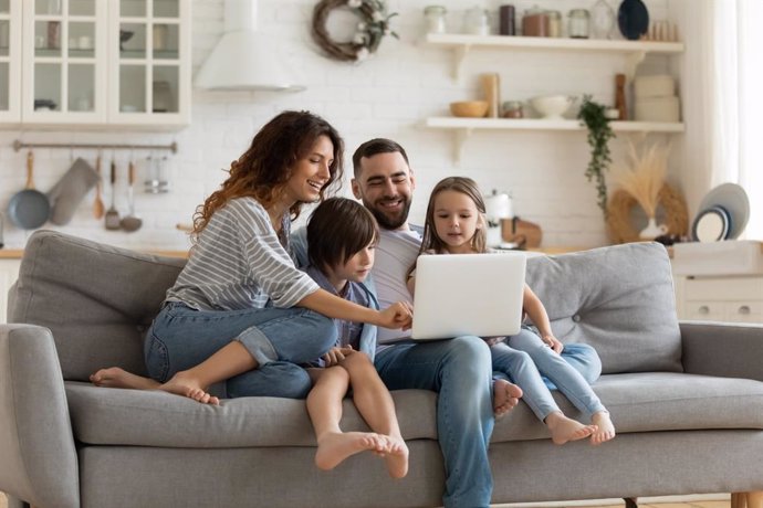 Familia feliz en casa mirando un ordenador.