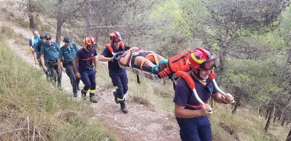 Los bomberos trasladan a la senderista accidentada en camilla hasta el lugar donde esperaba el vehículo 4x4 que la llevó hasta la ambulancia.
