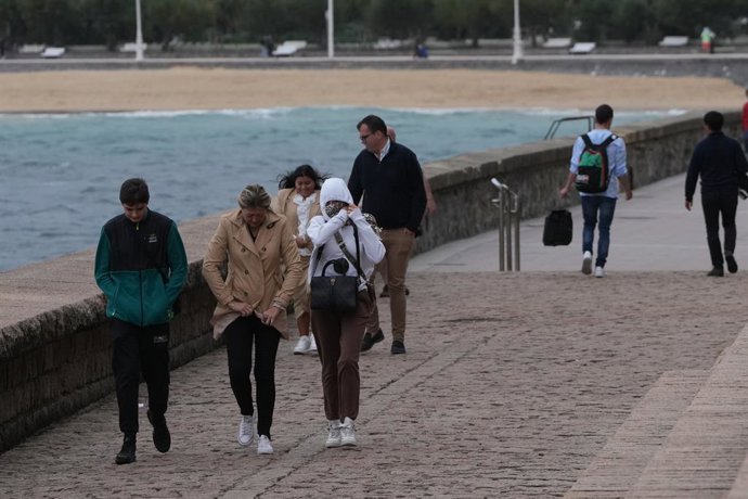 Varias personas caminan bajo la lluvia en la playa de Ondarreta, a 14 de octubre de 2023, en San Sebastián, Guipúzcoa, País Vasco (España).  