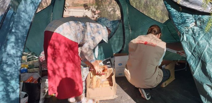 Una trabajadora de Cáritas junto a una mujer en una tienda de campaña en Marruecos.