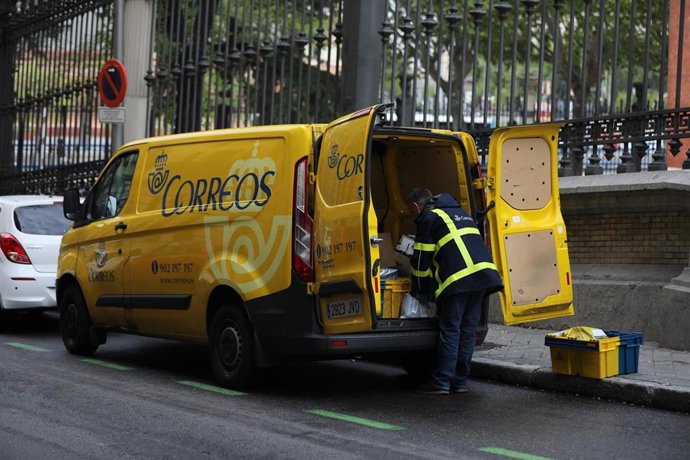Archivo - Un trabajador de Correos extrae de su furgoneta paquetes y cartas para repartir