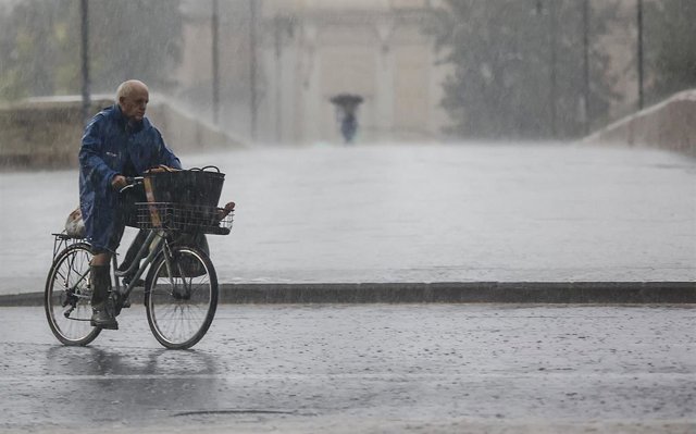 Archivo - Una persona en bicicleta bajo la lluvia, a 15 de septiembre de 2023, en València, Comunidad Valenciana (España). Las tormentas, en algunos casos de intensidad fuerte, están recorriendo durante las primeras horas de la mañana de este viernes los 
