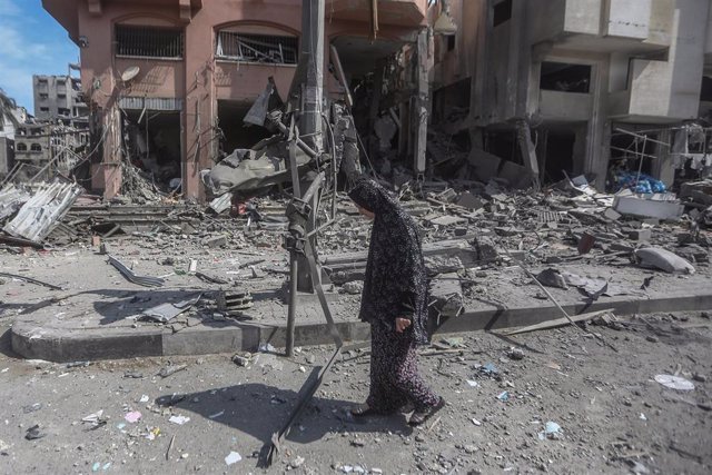 Una mujer palestina camina por una calle de Gaza tras el derrumbe de varios edificios por los ataques israelíes.