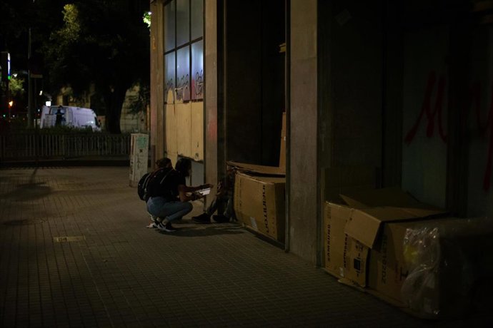 Archivo - Una voluntaria habla con personas que duermen en cajas de cartón.- Archivo