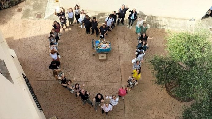 Socios, usuarios y trabajadores de la Fundación Patronato Obrero realizan un corazón humano durante el acto de entrega de alimentos.