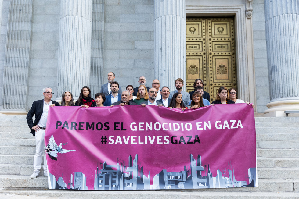 Varios diputados de diferentes grupos parlamentarios sostienen una pancarta que reza: "Paremos el genocidio en Gaza #savelivesgaza".