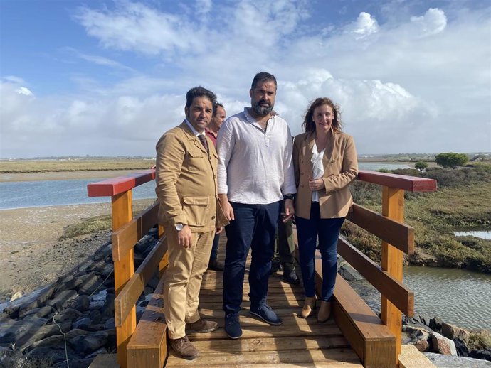 Autoridades en la colocación del nuevo puente del sendero 'Marismas de San Miguel', en Cartaya (Huelva).
