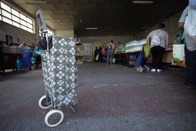 Archivo - Voluntarios atienden a las personas que vienen a buscar comida en el almacén de un banco de alimentos 