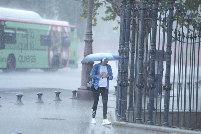 Una persona camina bajo la lluvia por el centro de la ciudad.