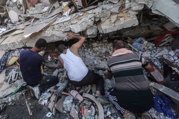 Palestins cercant víctimes entre els enderrocs d'un edifici a la Franja de Gaza