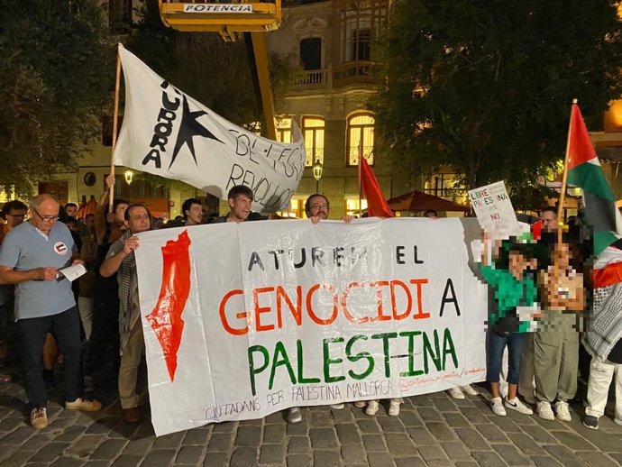 Varios asistentes a la concentración sujetan una pancarta con el lema 'Paremos el genocidio a Palestina'.