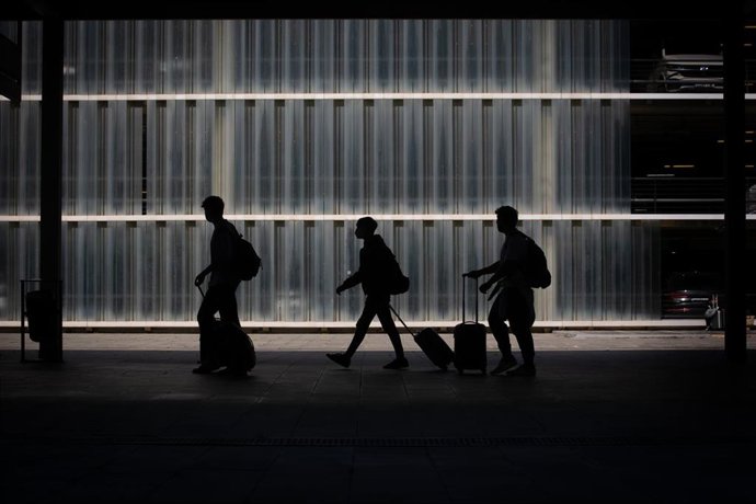 Archivo - Tres personas caminan junto a su equipaje en el Aeropuerto de Barcelona-El Prat, Barcelona, Catalunya (España).
