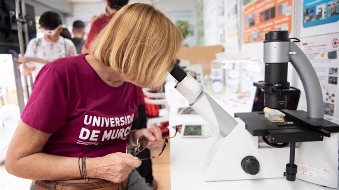 Una mujer observa a través de un microscopio en una foto de archivo de la Semana de la Ciencia y la Tecnología de la UMU