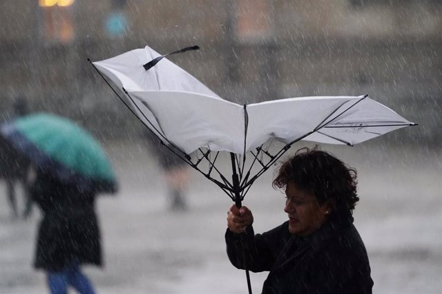 Una mujer sujeta un paraguas durante el paso de la borrasca ‘Aline’.