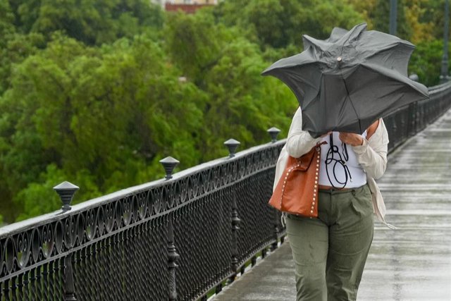 Dificultades de caminar por el Puente de Triana debido al viento y la lluvia