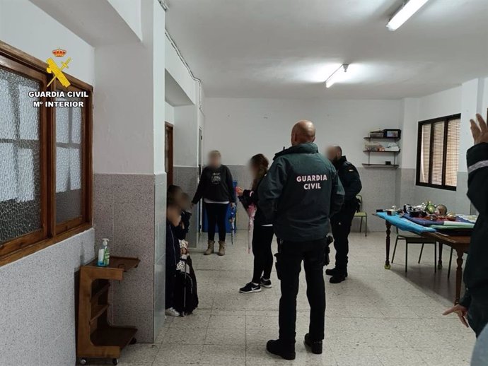 Agentes de la Guardia Civil evacuan a los escolares de Montánchez tras el desprendimiento de una claraboya.