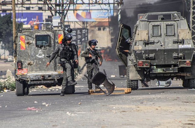 October 13, 2023, Nablus, West bank, Palestine: Israeli soldiers kick rubble off the ground placed by Palestinian demonstrators, during a demonstration in support of Gaza, which has been under Israeli air strikes since October 7, near the Hawwara checkpoi