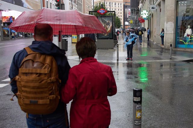 Archivo - Dos personas con paraguas caminan bajo la lluvia por el centro de Madrid 