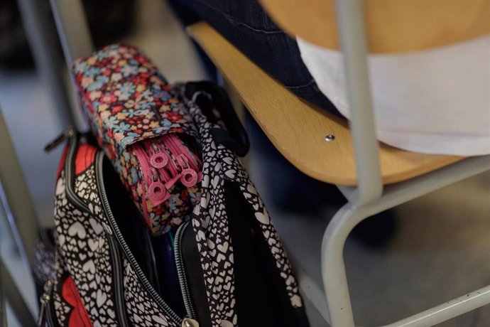 Archivo - Una mochila junto a la silla de un pupitre en un aula de colegio.