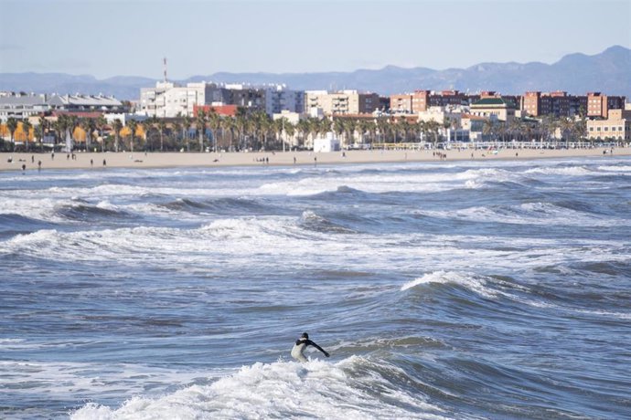 Archivo - Una persona surfea en la playa de la Malvarrosa