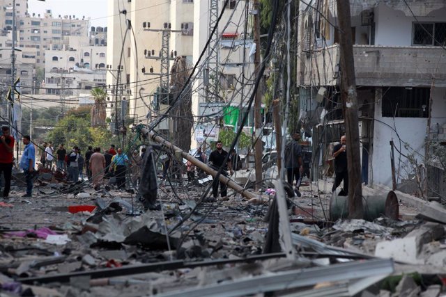October 11, 2023, Gaza city, Gaza Strip, Palestinian Territory: Palestinians walk through debris and destruction littering a street in al-Karama district in Gaza City on October 11, 2023, on the fifth day of battles between the Palestinian Islamist moveme