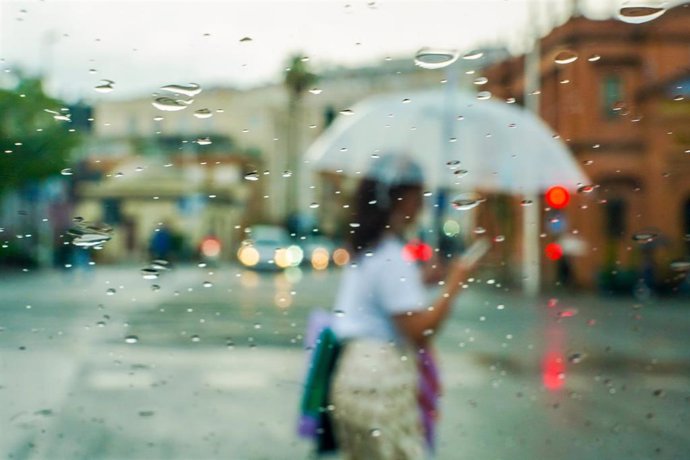 Archivo - Una mujer se protege de la lluvia con un paraguas.