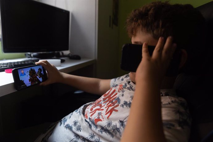 Un niño usa el teléfono móvil y una tablet, a 18 de octubre de 2023, en Madrid (España). Según la Vanguardia, en España se estima que el 21% de los adolescentes es adicto a la red y casi la mitad reconoce que tiene "un contacto activo" cada 15 minutos. 