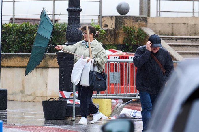 Varias personas tratan de cubrirse de la lluvia y el viento, a 20 de octubre de 2023, en Santander, Cantabria (España). La Agencia Estatal de Meteorologia ha decretado para hoy varios avisos por fenomenos meteorologicos adversos en Cantabria, los de ma
