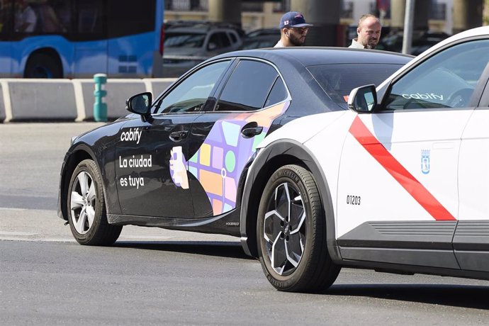 Archivo - Un taxi de Cabify al laso de un taxi en la zona de Atocha