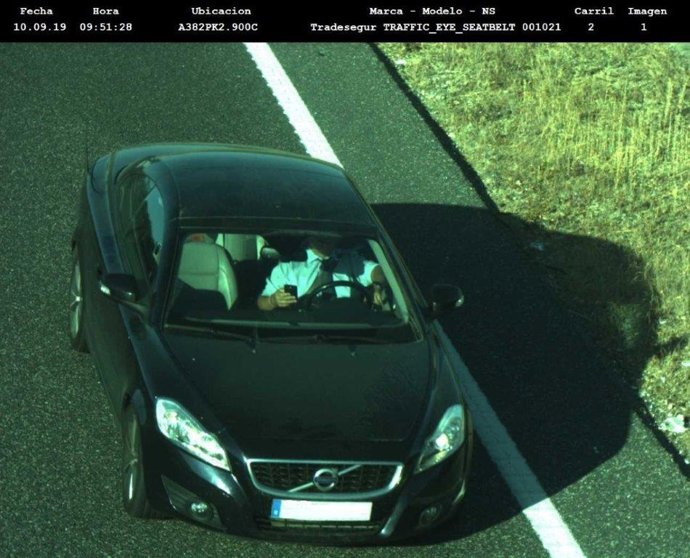 Archivo - Un conductor manipula su teléfono móvil mientras conduce.