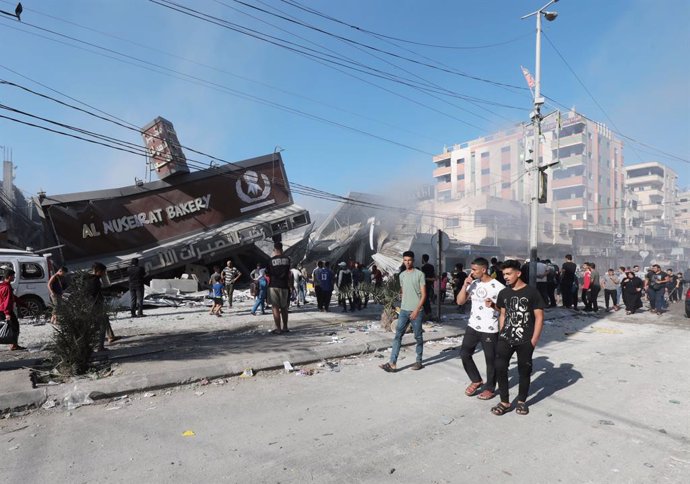 Un grupo de palestinos frente a una panadería destruida por un bombardeo de Israel contra la Franja de Gaza