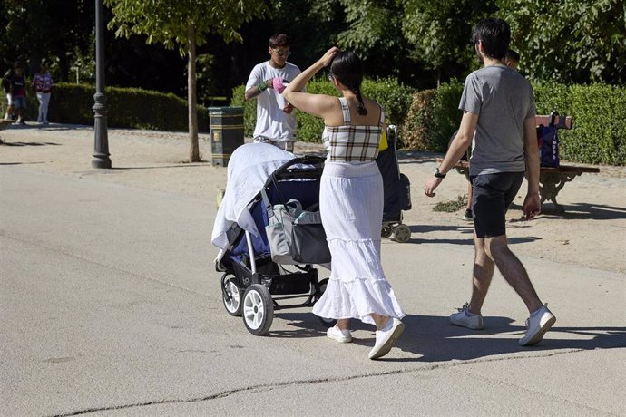 Archivo - Una pareja pasea con un carrito de bebé en el parque de El Retiro.