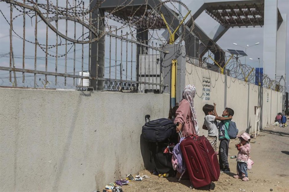 Niños con equipaje en el cruce fronterizo de Rafá, en el sur de la Franja de Gaza, mientras los palestinos, algunos con pasaportes extranjeros, esperan ayuda y un posible cruce a Egipto