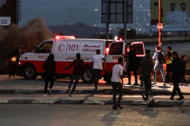 Palestinos corren hacia una ambulancia durante los enfrentamientos con las fuerzas de seguridad israelíes en la aldea de Huwara, en Cisjordania