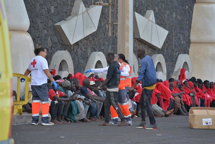 Trabajadores de la Cruz Roja al lado de los migrantes que han llegado en un cayuco al puerto de La Restinga, a 23 de octubre de 2023, en El Hierro, Santa Cruz de Tenerife, Tenerife, Canarias (España). La embarcación de Salvamento Marítimo, Salvamar Adha