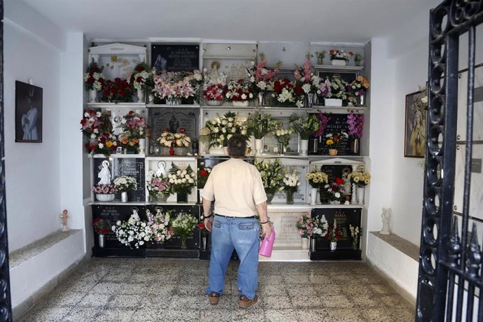 Archivo - Un hombre riega las  flores colocadas en la tumba de un ser querido.