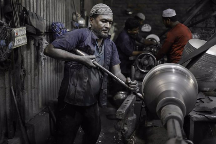 Archivo - May 24, 2023, Dhaka, Bangladesh: Labors who earn $5 a day polish silver pots at a manufacturing factory at Kamrangir Char area in Dhaka.