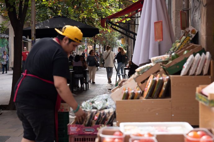 Un dependent colloca fruita en un estand en l'exterior.