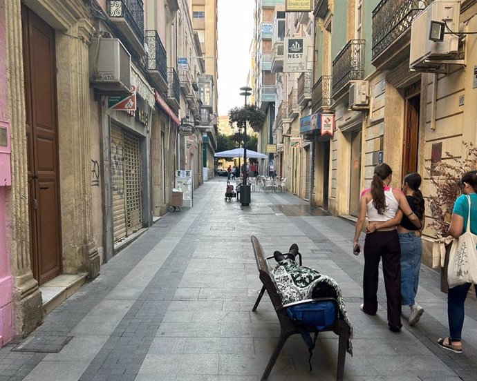 Una persona duerme en un banco situado en una calle del centro histórico de Almería.